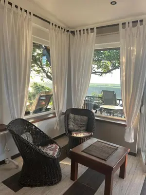 a living room with chairs and a table and a window at Panorama Beska in Beška