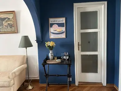 a room with a blue wall with a table and a door at Cozy aparts in the city heart in Belgrade