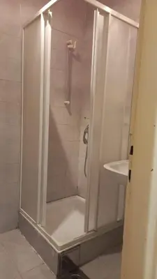 a shower with a glass door next to a sink at August in Belgrade
