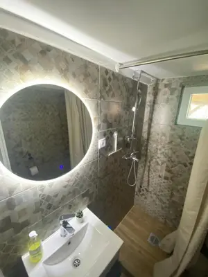 a bathroom with a sink and a shower with a mirror at Elephant House-Sd