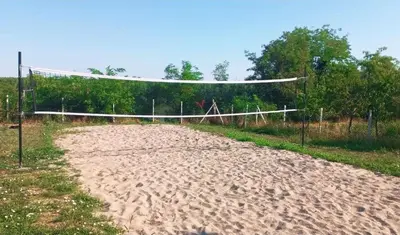 a volleyball net on a sandy field with trees at Vila Aleksandar in Krčedin