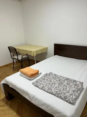 a bedroom with a bed and a table with a chair at Aliyah Hostel in Belgrade