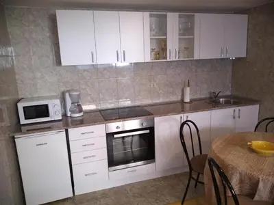 a kitchen with white cabinets and a table and a microwave at Apartment Vojinovic in Arandjelovac