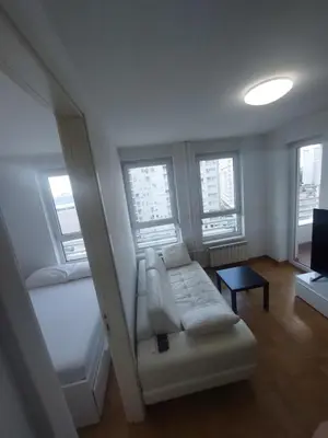 a living room with a couch and a bed and windows at DELTA CITY Apartment in Novi Beograd