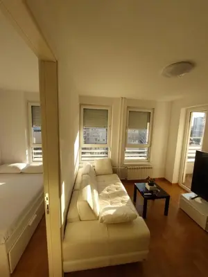 a living room with a couch and a bed and windows at DELTA CITY Apartment in Novi Beograd