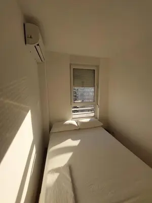 a bed in a small room with a window at DELTA CITY Apartment in Novi Beograd