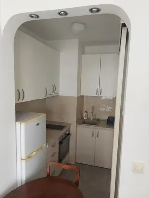 a small kitchen with white cabinets and a table at DELTA CITY Apartment in Novi Beograd