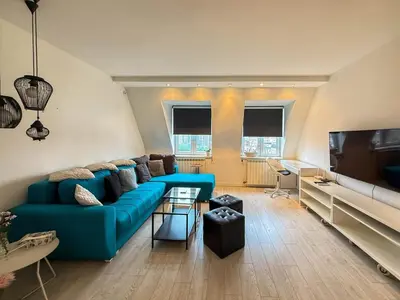 a living room with a blue couch and a flat screen tv at Downtown Cozy Apartment in Belgrade