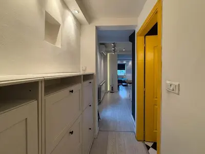 a kitchen with white cabinets and a hallway with a yellow door at Downtown Cozy Apartment in Belgrade
