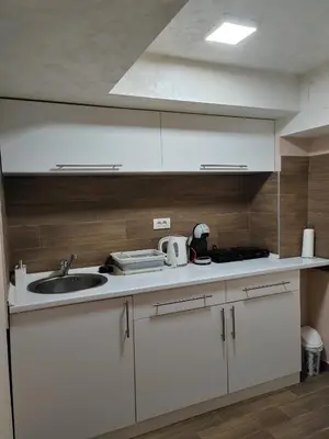a kitchen with white cabinets and a sink at Jacuzzi Apartman PK Pančevo in Pančevo