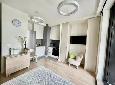 a living room with a chair and a clock on the wall at BW Studio Metropolitan in Belgrade