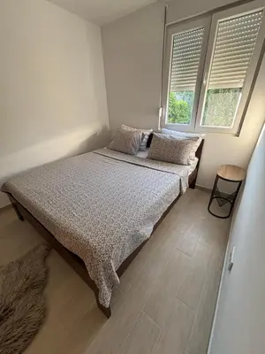 a bedroom with a bed with two pillows and two windows at Zemun ES stan na dan in Belgrade