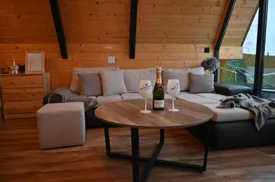 a living room with a couch and a table with a bottle of champagne at A-Frame Wellness Villa with Private Pool, Sauna & Jacuzzi near Belgrade in Koraćica