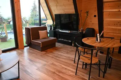 a living room with a television and a table and chairs at A-Frame Wellness Villa with Private Pool, Sauna & Jacuzzi near Belgrade in Koraćica