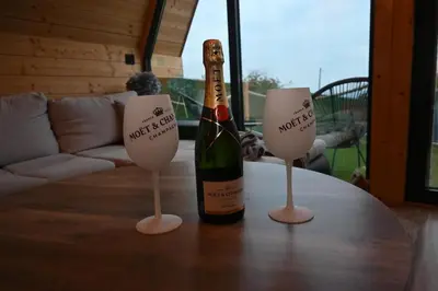 a bottle of wine sitting on a table with two wine glasses at A-Frame Wellness Villa with Private Pool, Sauna & Jacuzzi near Belgrade in Koraćica