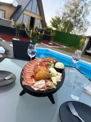 a plate of food on a table with wine glasses at A-Frame Wellness Villa with Private Pool, Sauna & Jacuzzi near Belgrade in Koraćica