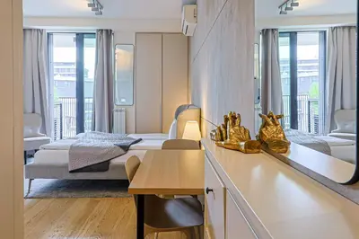 a bedroom with two beds and a desk with a table at ZIGZAG Belgrade Waterfront Metropoliten in Belgrade