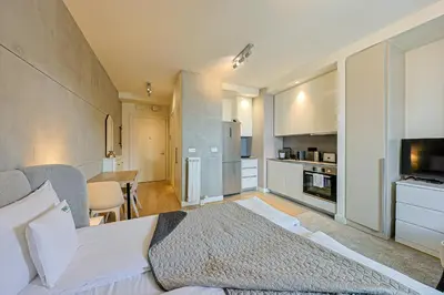 a bedroom with a large bed and a kitchen at ZIGZAG Belgrade Waterfront Metropoliten in Belgrade