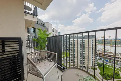 a balcony with a chair and a view of a city at ZIGZAG Belgrade Waterfront Metropoliten in Belgrade