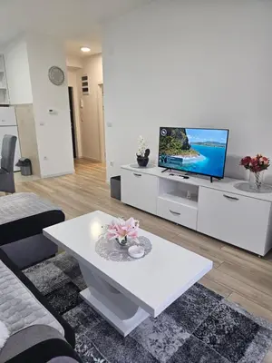 a living room with a tv and a white table at Miss LuX in Mladenovac