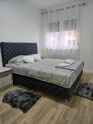 a bed in a bedroom with two rugs on it at Miss LuX in Mladenovac