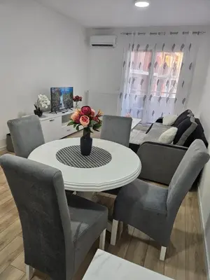 a dining room with a white table and chairs at Miss LuX in Mladenovac