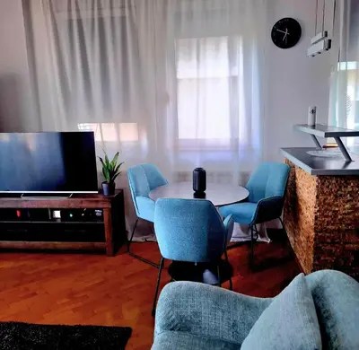 a living room with a table and chairs and a television at BelMont Vračar in Belgrade