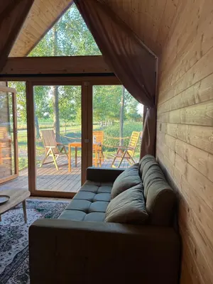 a couch sitting in a living room with a window at Ritopia Glamping in Kovilj