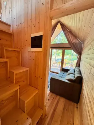 a room with a couch in a wooden cabin at Ritopia Glamping in Kovilj