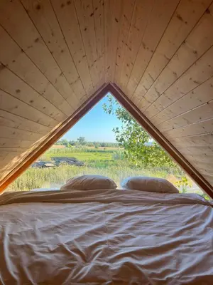 a bed in a tent with a large window at Ritopia Glamping in Kovilj