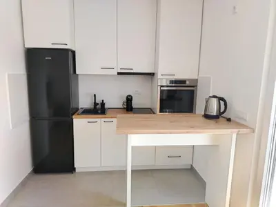 a kitchen with white cabinets and a wooden counter top at EXPO Prime New Belgrade Ledine in Ledine