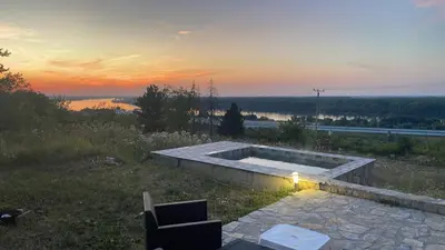 a hot tub on a hill with a sunset in the background at Kuća sa Pogledom in Sremski Karlovci