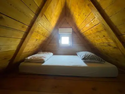 a bed in a wooden room with a window at Kuća sa Pogledom in Sremski Karlovci