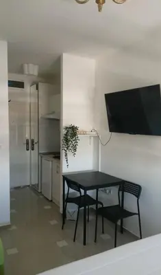 a dining room table with two chairs and a tv on a wall at Ogi apartment Beograd in Belgrade