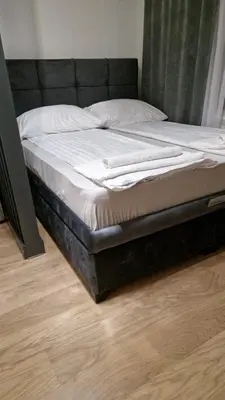 a bed with a black bed frame on a wooden floor at Sava Lux in Sajmište