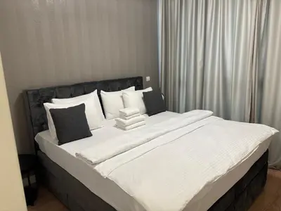 a large bed with white sheets and black pillows at BW AQUA Joi Lux 2 Apartment in Belgrade
