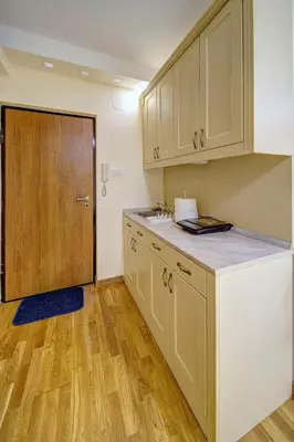 a kitchen with white cabinets and a wooden door at Oasis Moonze in Zemun