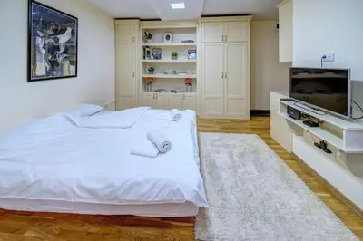 a white bedroom with a bed and a tv at Oasis Moonze in Zemun