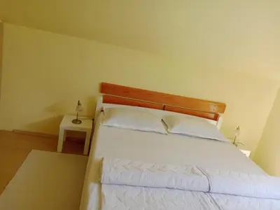 a bedroom with a white bed with a wooden headboard at Stan Na Dan - Mladenovac in Mladenovac