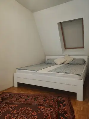 a bed in a room with a window and a rug at Urban nest Slavija in Belgrade