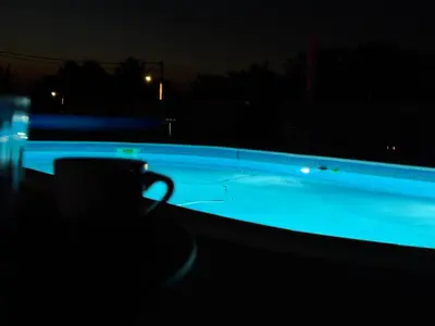 a swimming pool at night with a cup in the dark at Forest House in Beljina