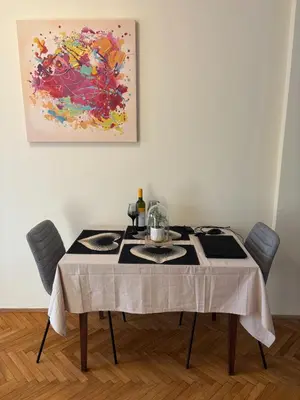 a dining room table with chairs and a painting on the wall at Urban Yard Retreat in Belgrade
