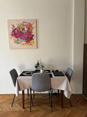 a dining room table with chairs and a painting on the wall at Urban Yard Retreat in Belgrade