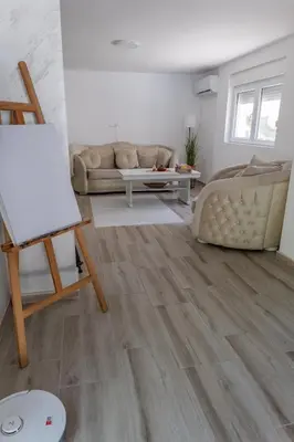 a living room with wood floors and a couch at Vila Peščana Tišina in Banatski Karlovac