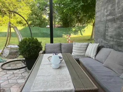 a gray couch with a table and a swing at Vila Peščana Tišina in Banatski Karlovac