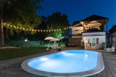 a swimming pool in the yard of a house at night at Vila Peščana Tišina in Banatski Karlovac