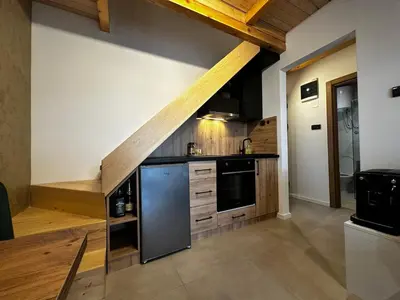 a kitchen with wooden cabinets and a black refrigerator at Taca House - Airport apartman in Surčin