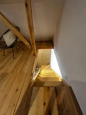 an attic room with a wooden floor and a chair at Taca House - Airport apartman in Surčin