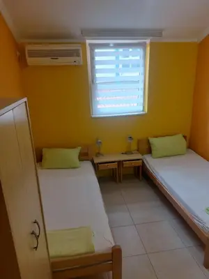 two beds in a room with a window at Maja Rooms & Garden in Smederevo