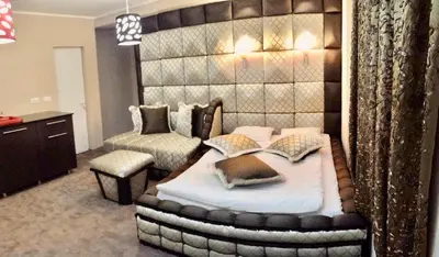 a bedroom with a large bed and a chair at Bali Colosseum Hotel in Belgrade